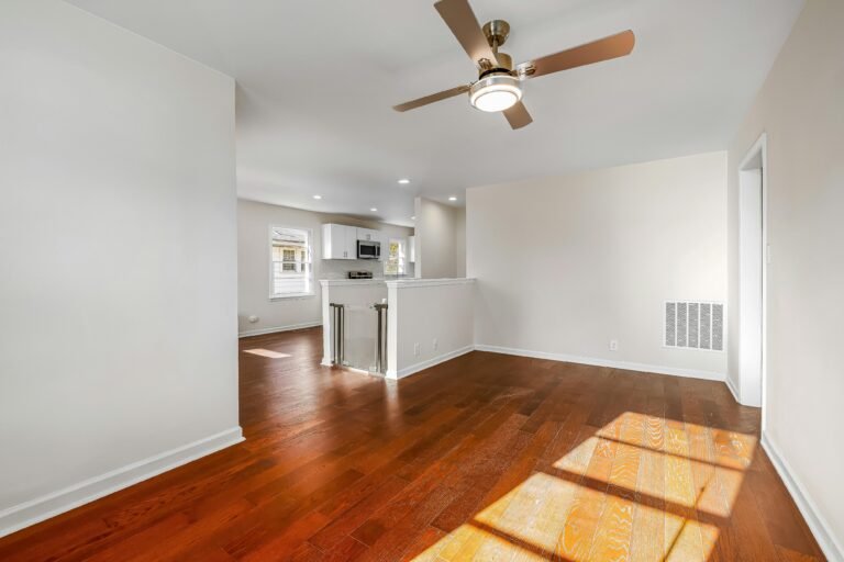 Spacious empty living room with wood floors and ceiling fan in open concept apartment.